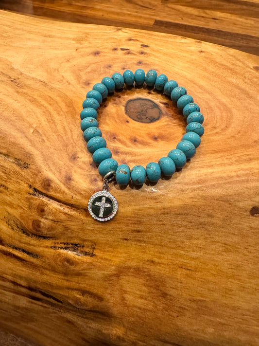 Turquoise stone beaded bracelet with crystal cross charm.